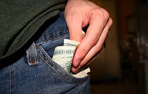 Hand pulling couple of dollar bills from his pocket